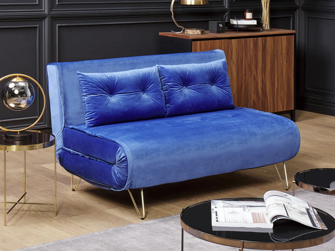 Blue velvet sofa in a stylish room with a wooden cabinet and round tables.