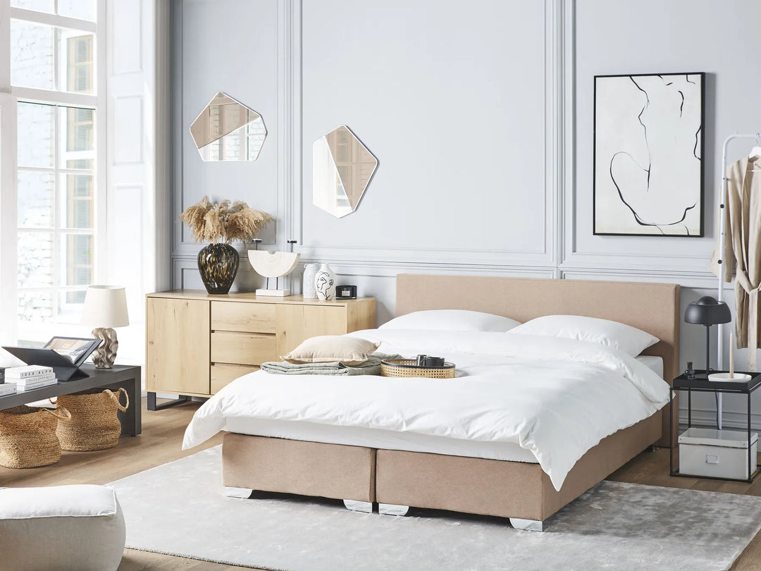 Modern bedroom with a beige bed, side tables, and decorative items.