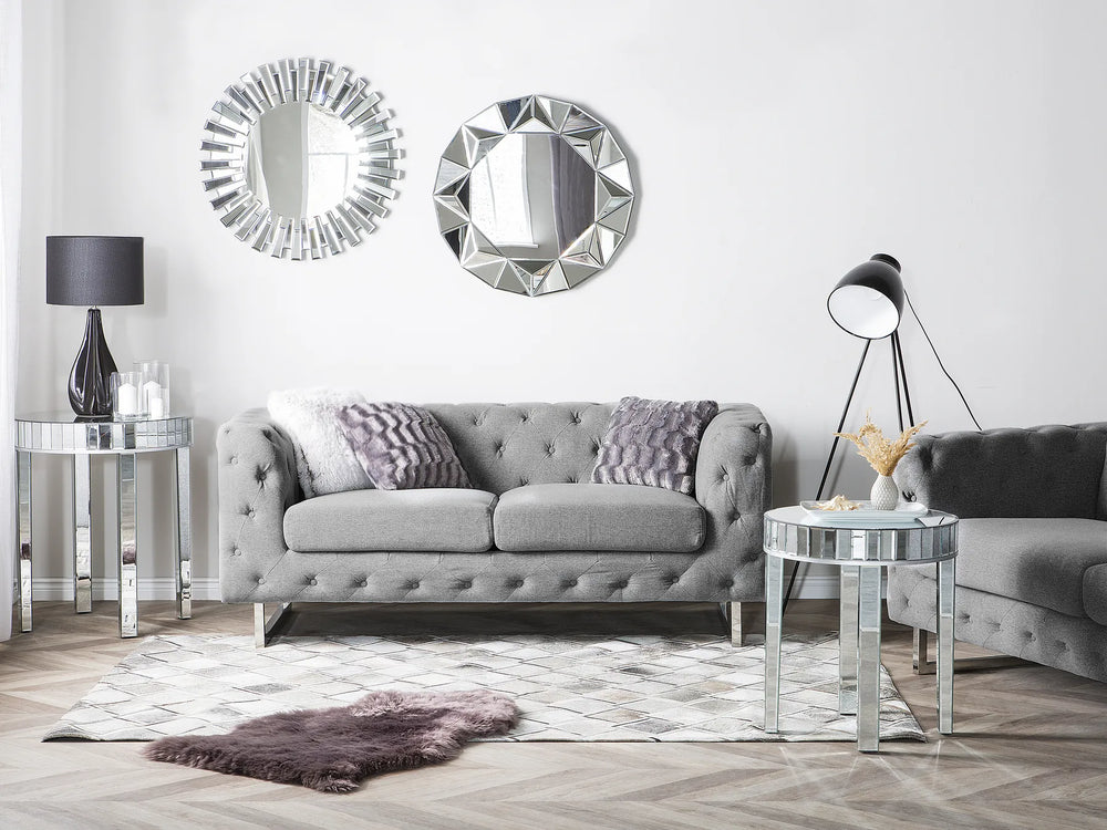 Modern living room with gray sofa, decorative mirrors, and side tables.