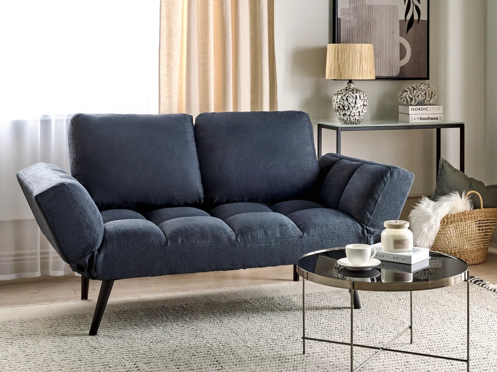 Blue sofa in a living room setting with a coffee table and decorative items.