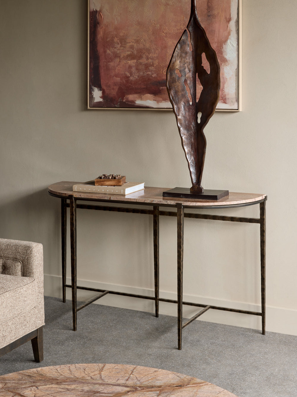 Console table with a bronze sculpture and books against a wall with abstract art.