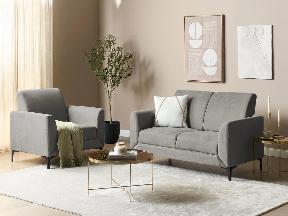 Modern living room with gray sofa and armchair, gold coffee table, and abstract wall art.