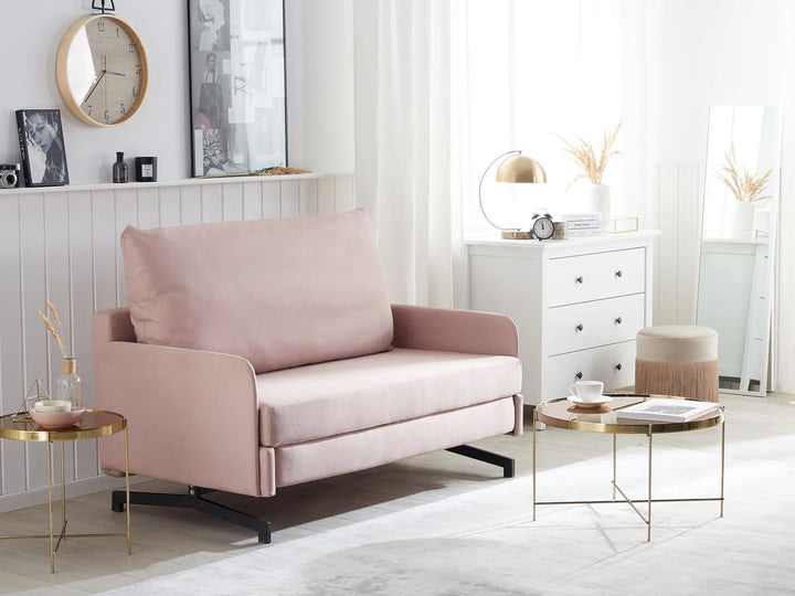 Pink sofa in a modern living room with white walls and gold side tables.