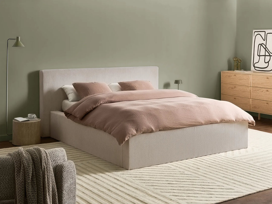 Neatly made bed with pink bedding in a bedroom setting.