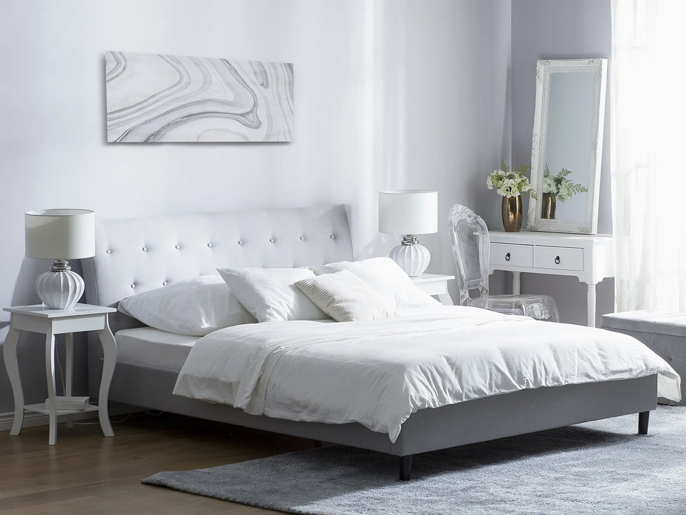 Modern bedroom with a gray bed, white bedding, and decorative items.