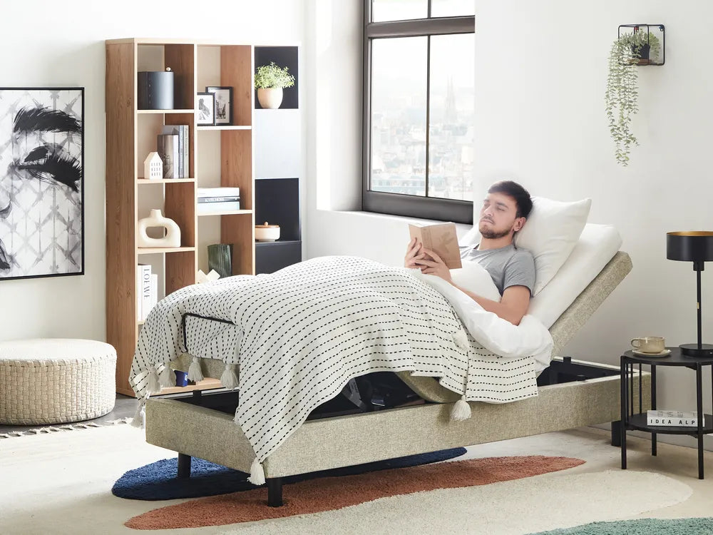 Man lying on a adjustable bed reading a book in a modern living room.
