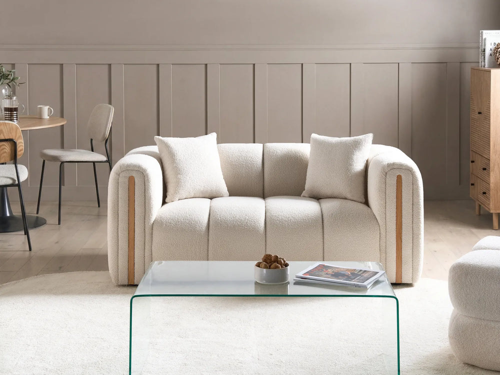 Beige sofa in a living room with a glass coffee table and decorative items.