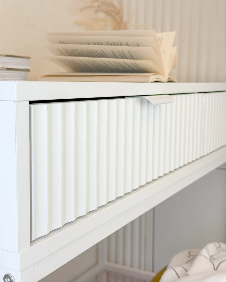 White bookshelf with decorative items against a neutral wall