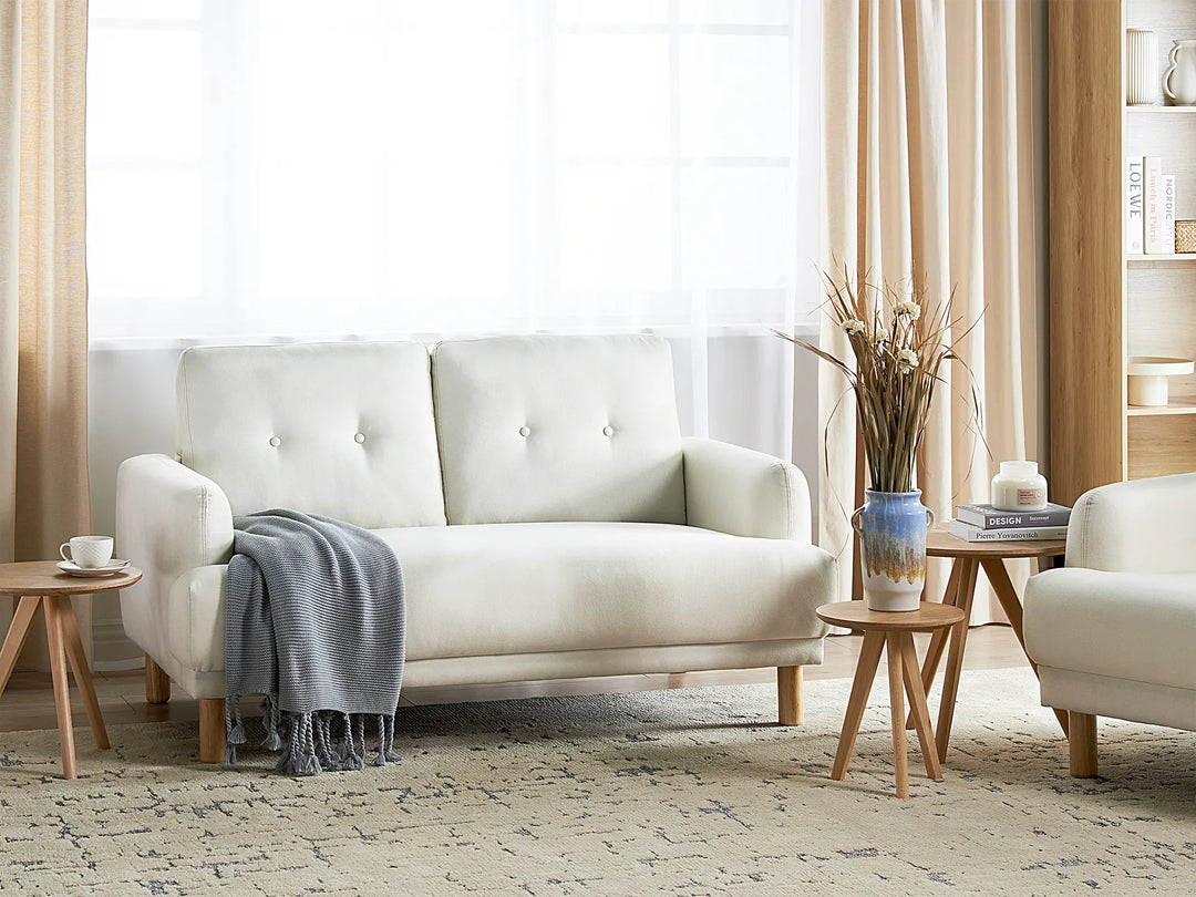 Modern living room with a white sofa, side tables, and decorative items.