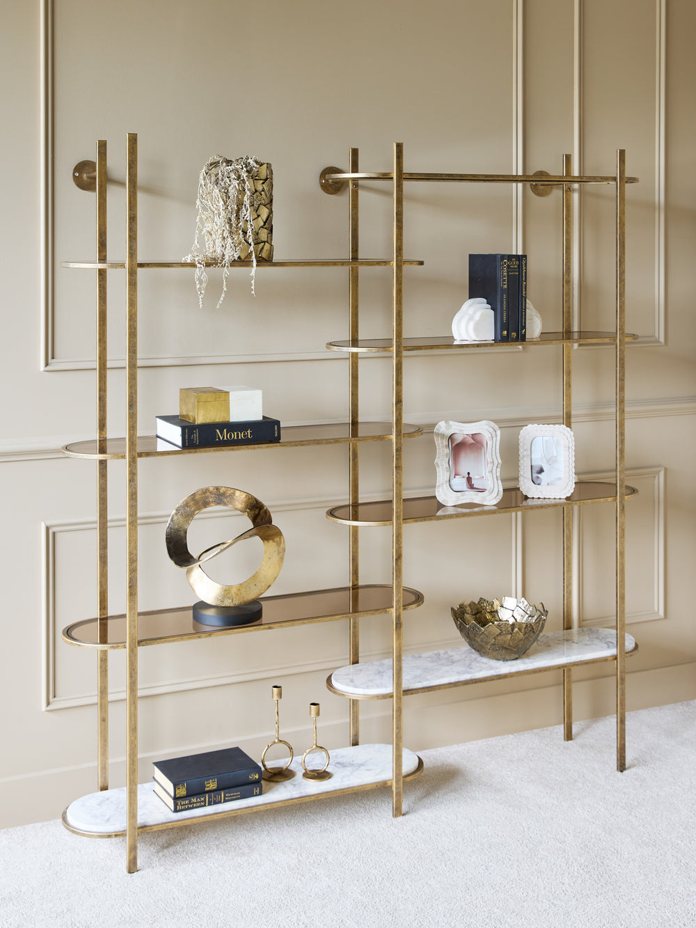 Gold and marble shelf unit with decorative items against a neutral wall.