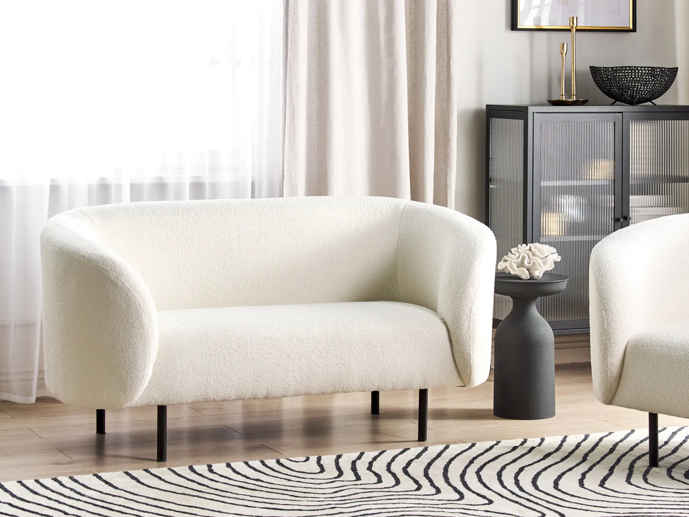 White armchair in a living room setting with a zebra-patterned rug and a side table.