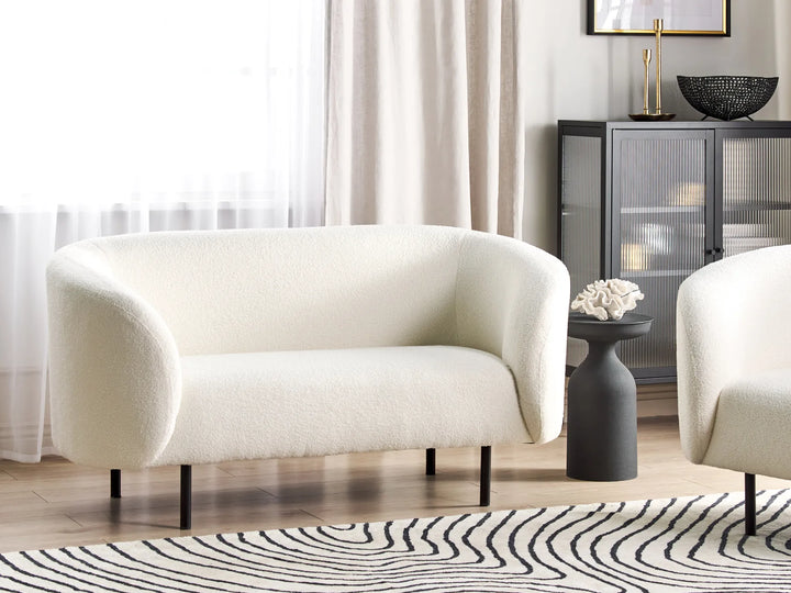 White armchair in a living room setting with a zebra-patterned rug and a side table.