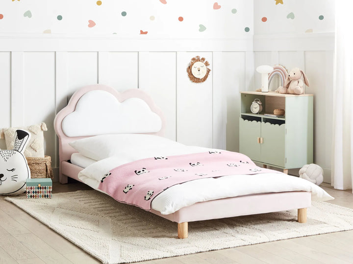 Children's bedroom with a pink bed and decorative items on a white wall.