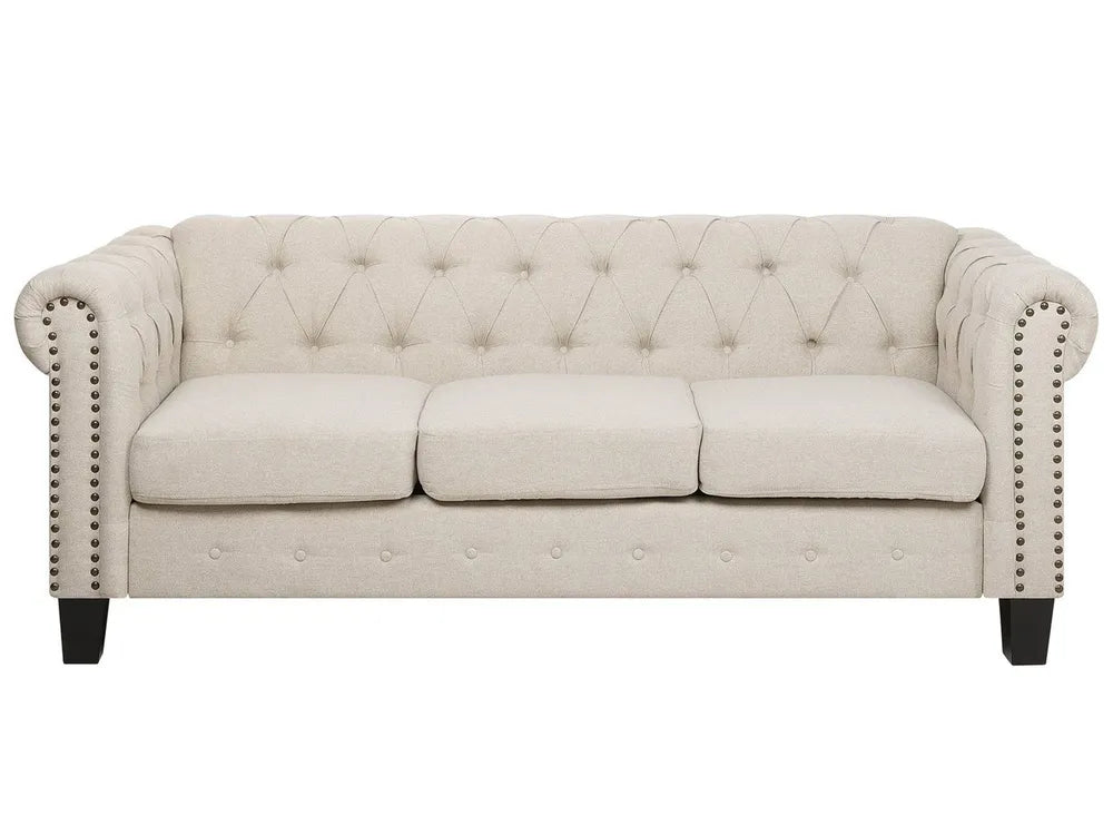 Beige tufted sofa with nailhead trim on a white background