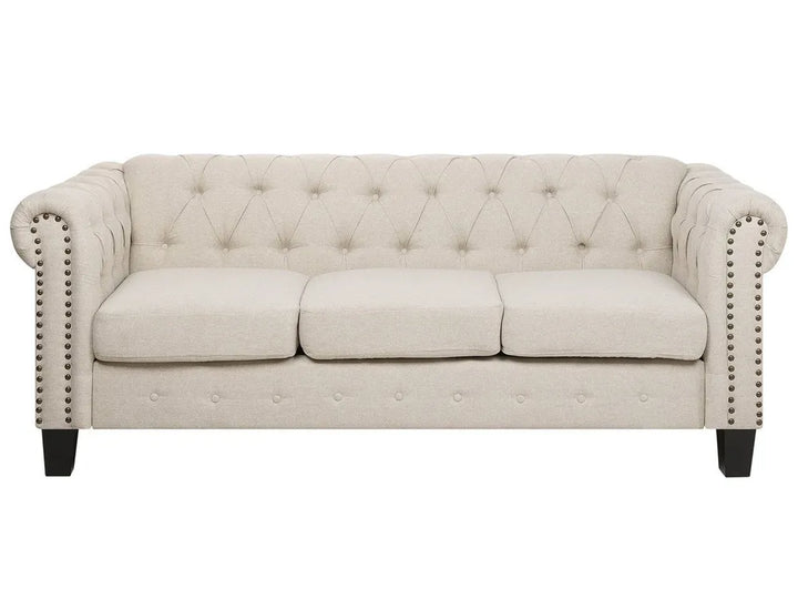 Beige tufted sofa with nailhead trim on a white background