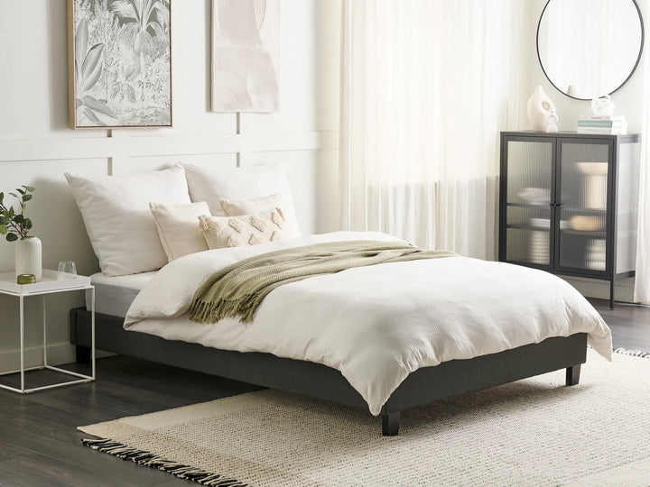 Neatly made bed in a bedroom with white bedding and decorative pillows.