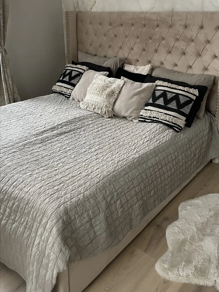 Bedroom with a bed featuring patterned pillows and a textured headboard.
