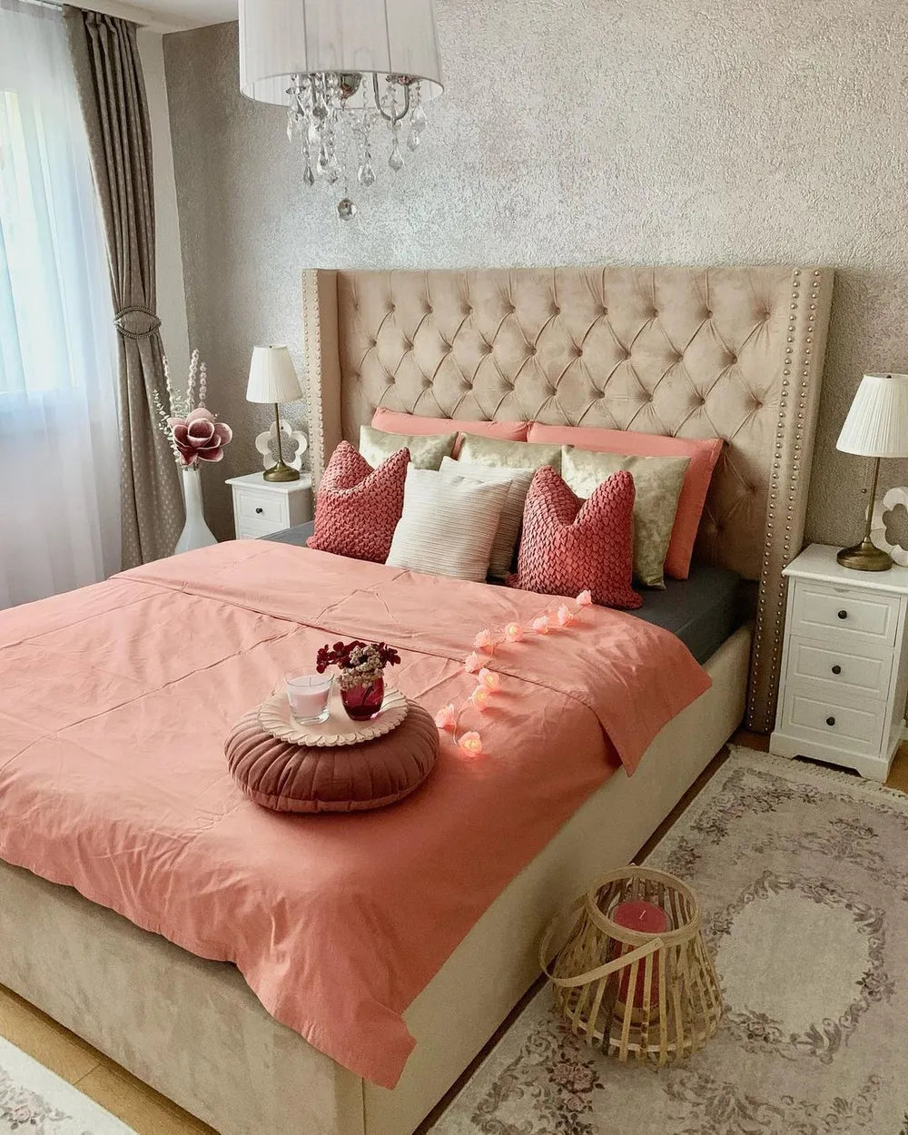 Neatly made bed with pink bedding and decorative pillows in a bedroom setting.