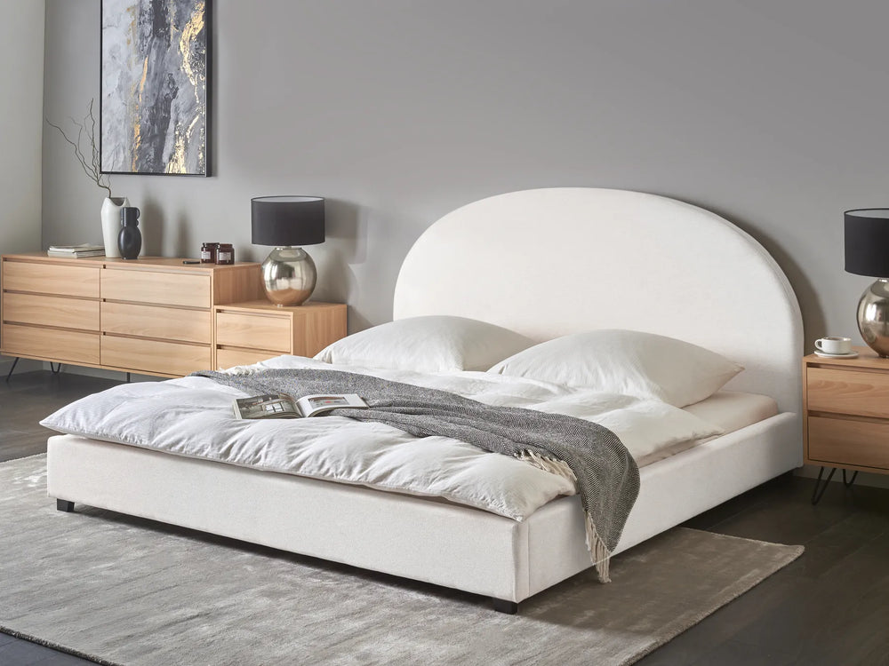Modern bedroom with a white upholstered bed, wooden nightstands, and decorative items.