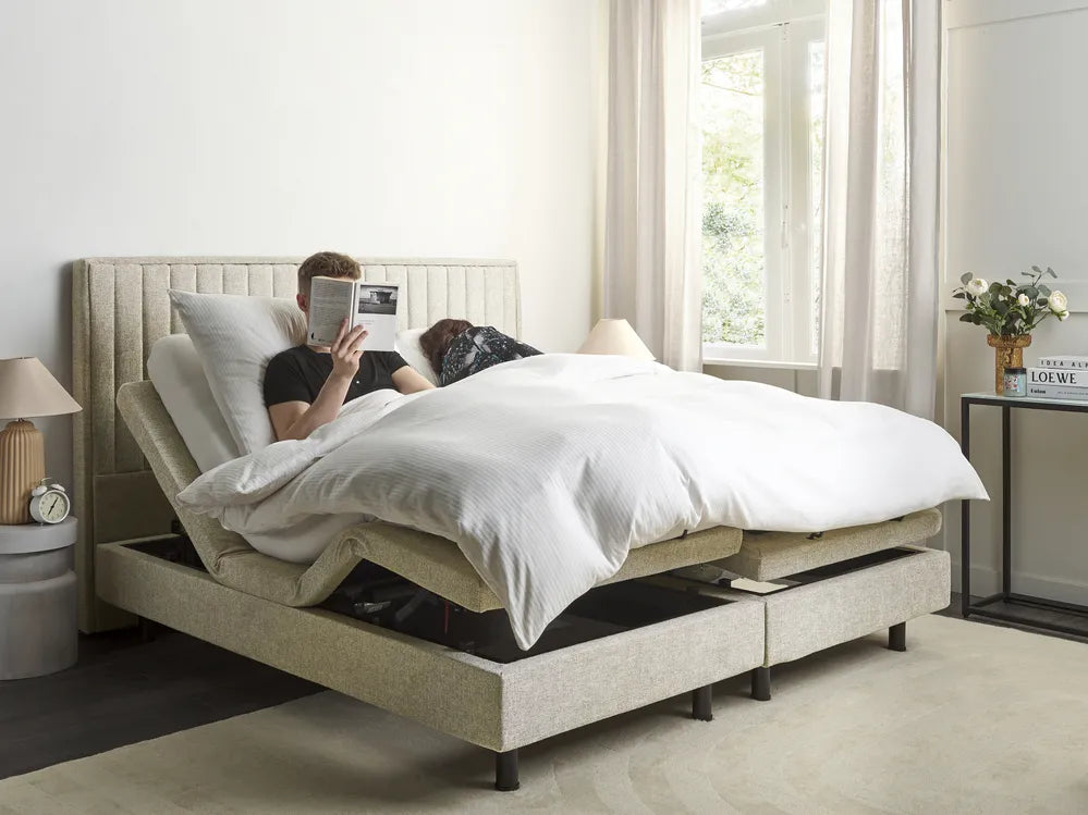 Two people using a adjustable bed in a bright bedroom.
