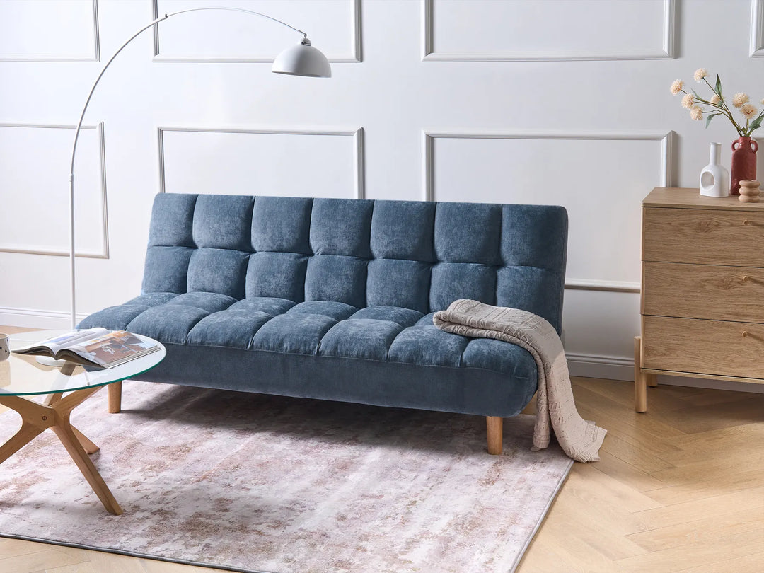 Blue sofa in a living room setting with a wooden cabinet and decorative items.