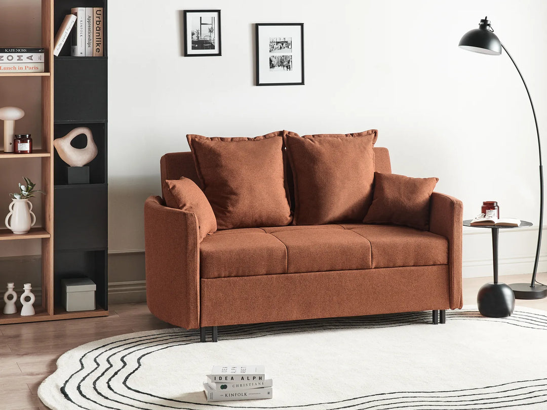 Brown sofa in a living room setting with a bookshelf and lamp.