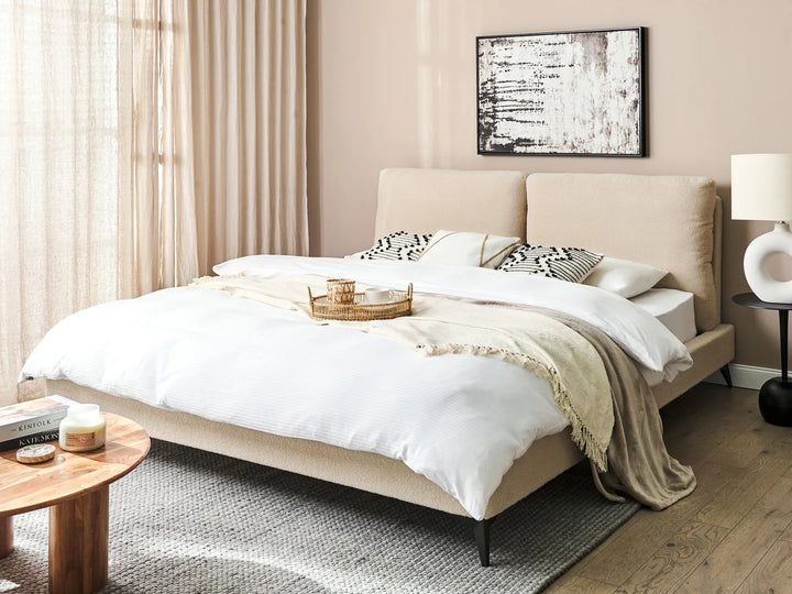 Neatly made bed in a bedroom with a side table and lamp.