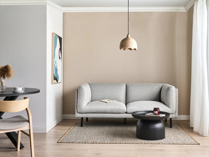 Modern living room with a gray sofa, round black coffee table, and pendant light.