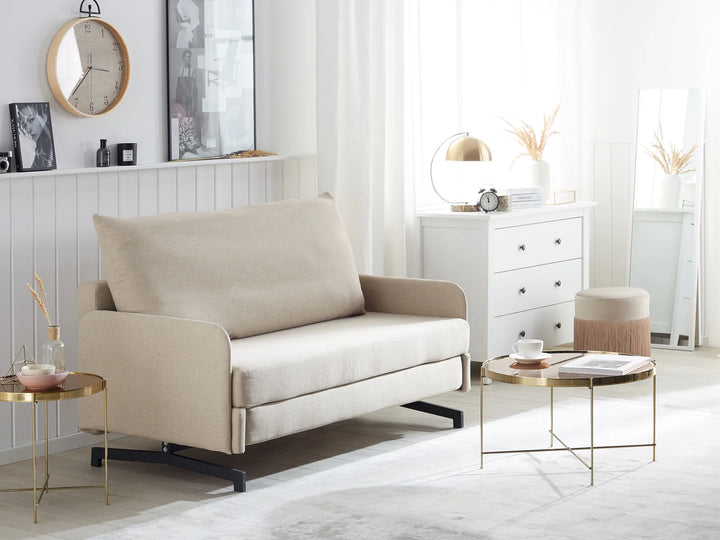 Beige sofa in a modern living room with white walls and decorative items.