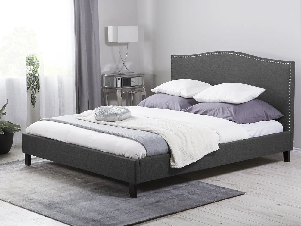 Gray upholstered bed with white bedding in a bedroom setting