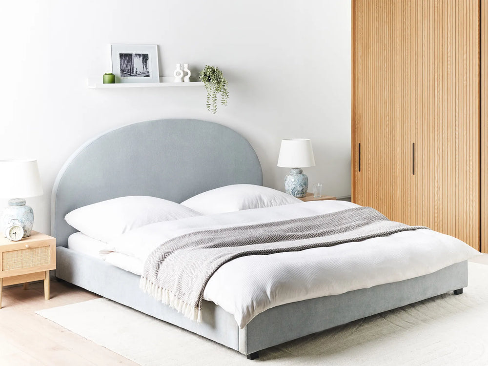 Gray upholstered bed in a bedroom with wooden wardrobe and nightstands.