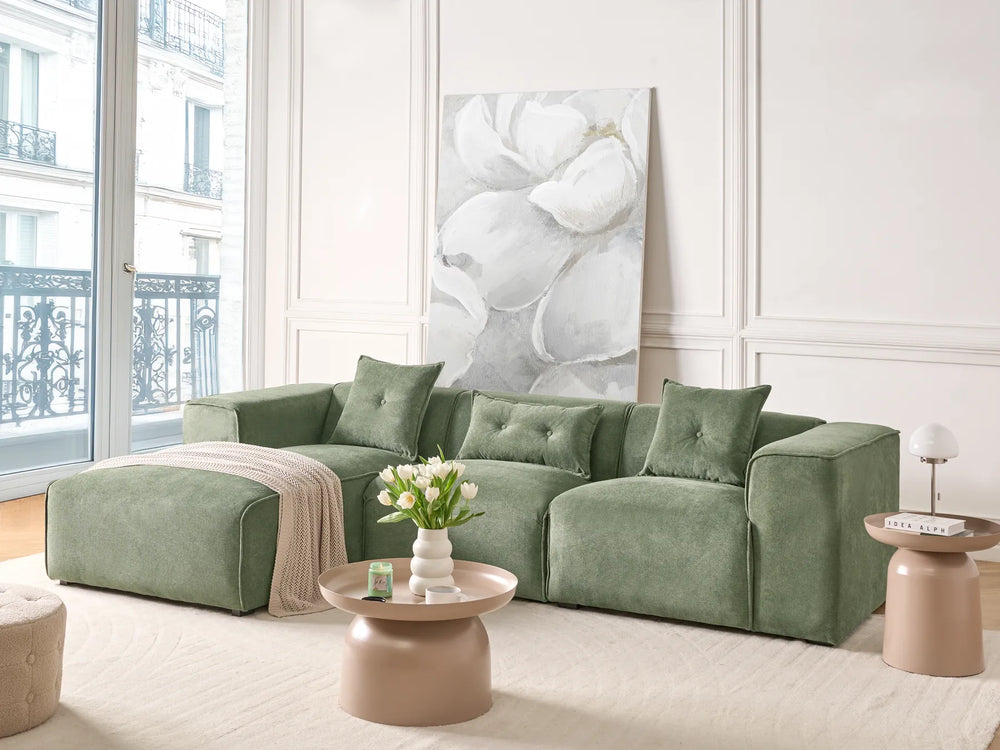 Green sofa in a living room with a large abstract painting on the wall.