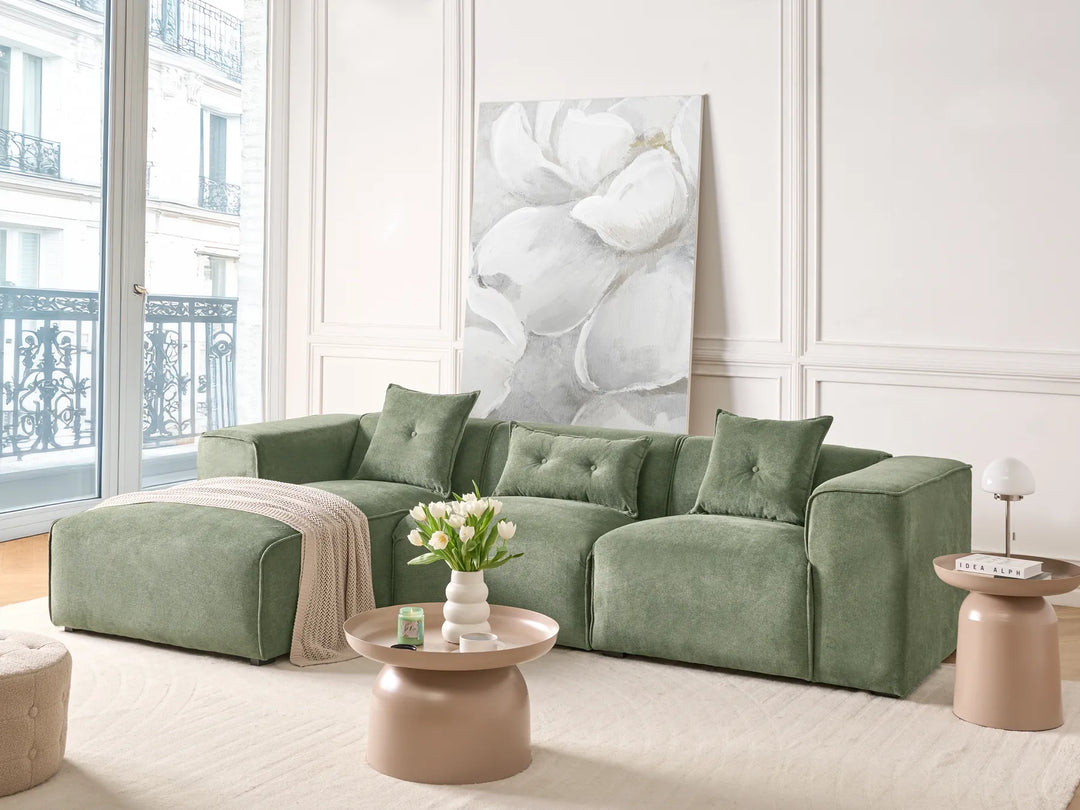 Green sofa in a living room with a large abstract painting on the wall.