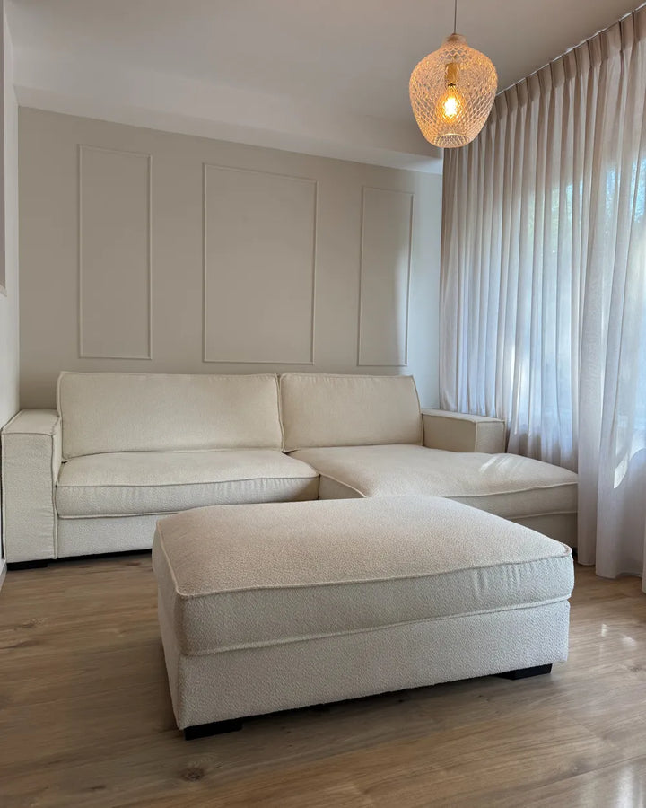 Beige sectional sofa with matching ottoman in a living room setting.