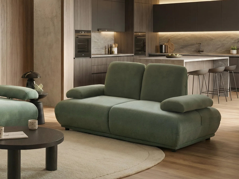 Green sofa in a modern living room with kitchen in the background