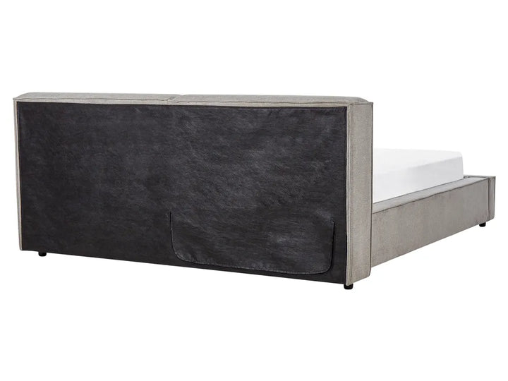 Bed with a dark upholstered headboard on a white background