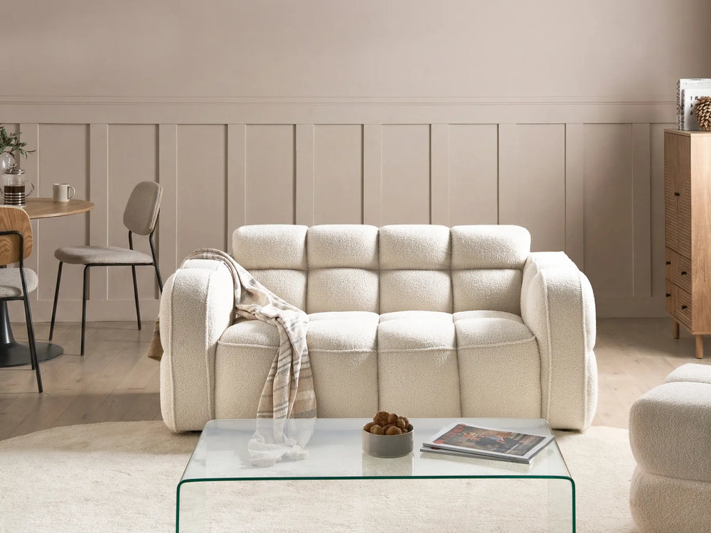 Beige sofa in a living room with a glass coffee table and neutral decor.