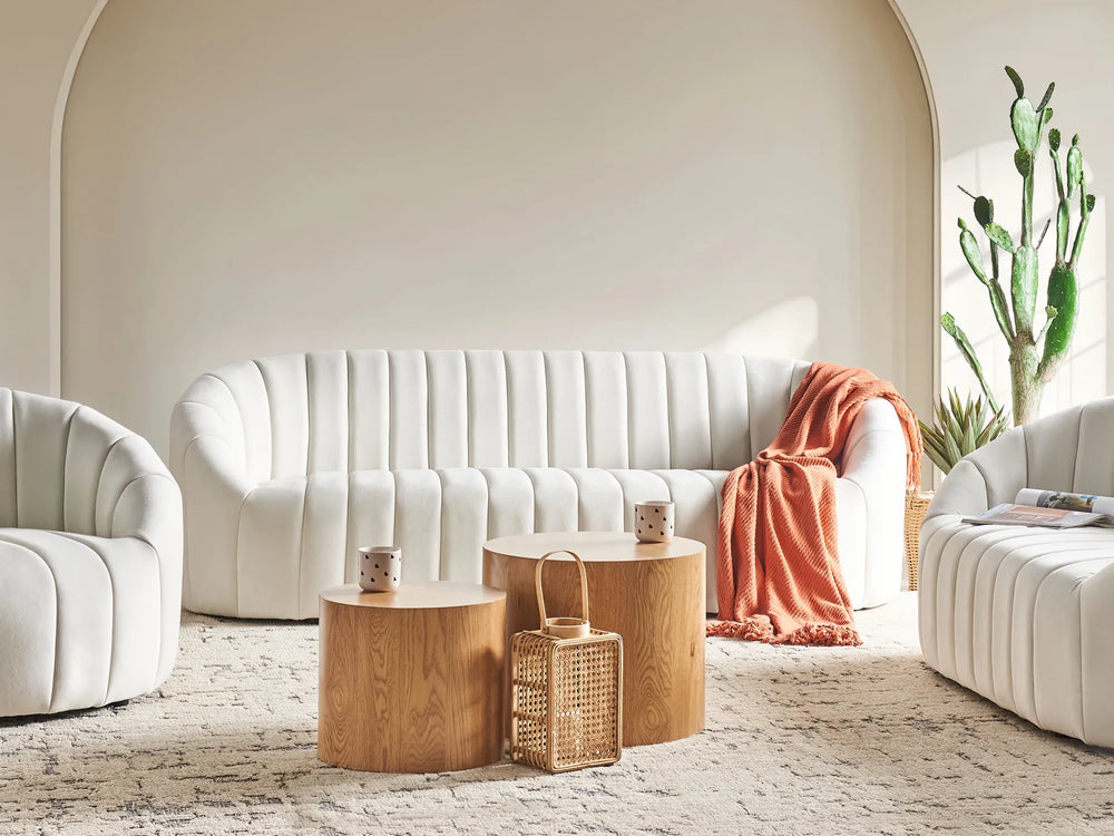Modern living room with white sofa, wooden coffee tables, and decorative items.
