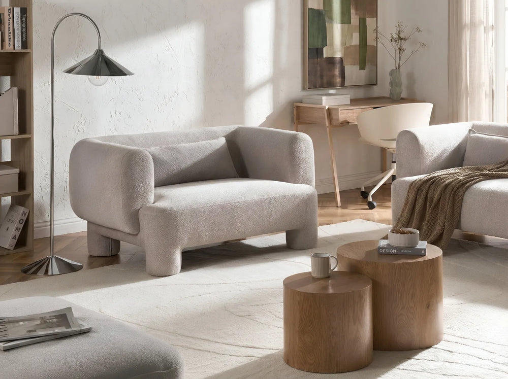 Modern living room with gray sofa, wooden coffee tables, and a lamp.