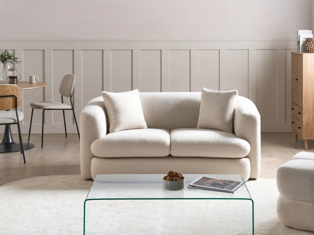 Beige sofa in a modern living room with a glass coffee table and neutral decor.