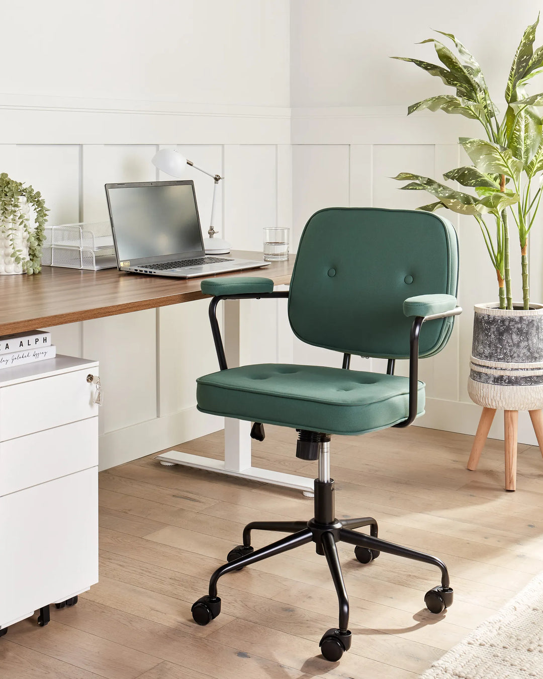 Green office chair in front of a desk with a laptop in a home office setting.