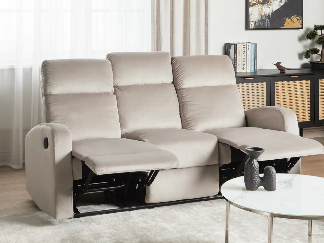 Beige recliner sofa in a living room setting with a coffee table and decor items.