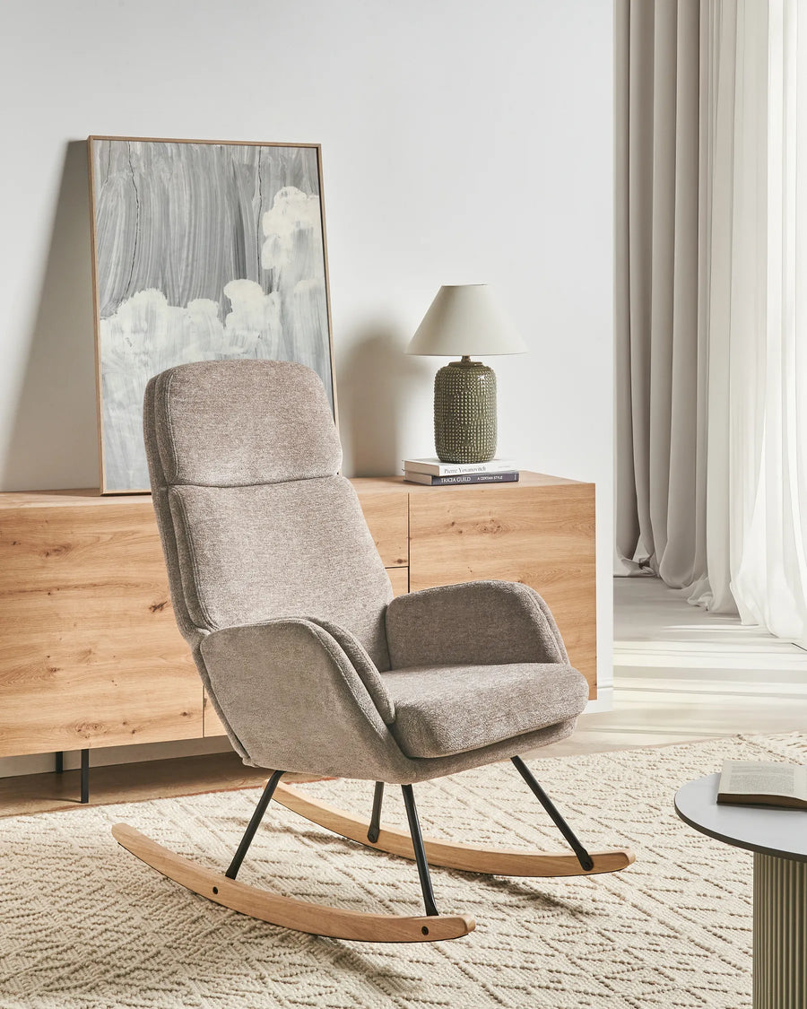 Gray rocking chair in a modern living room with wooden sideboard and lamp.