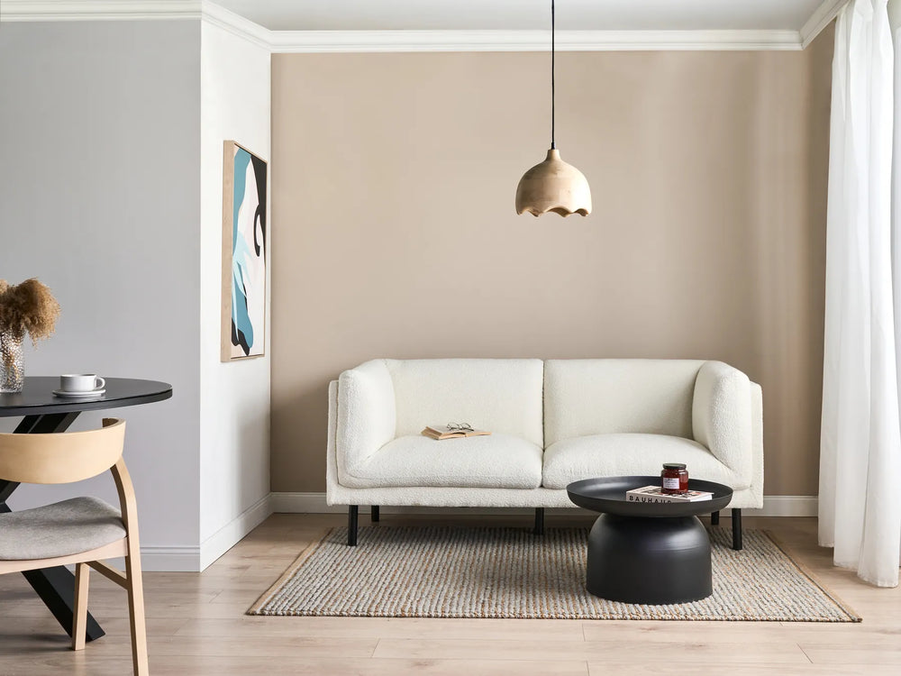 Modern living room with a white sofa, black coffee table, and wooden chair.