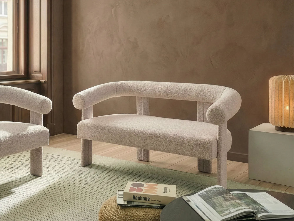Beige armchair in a room with a lamp and books on a rug