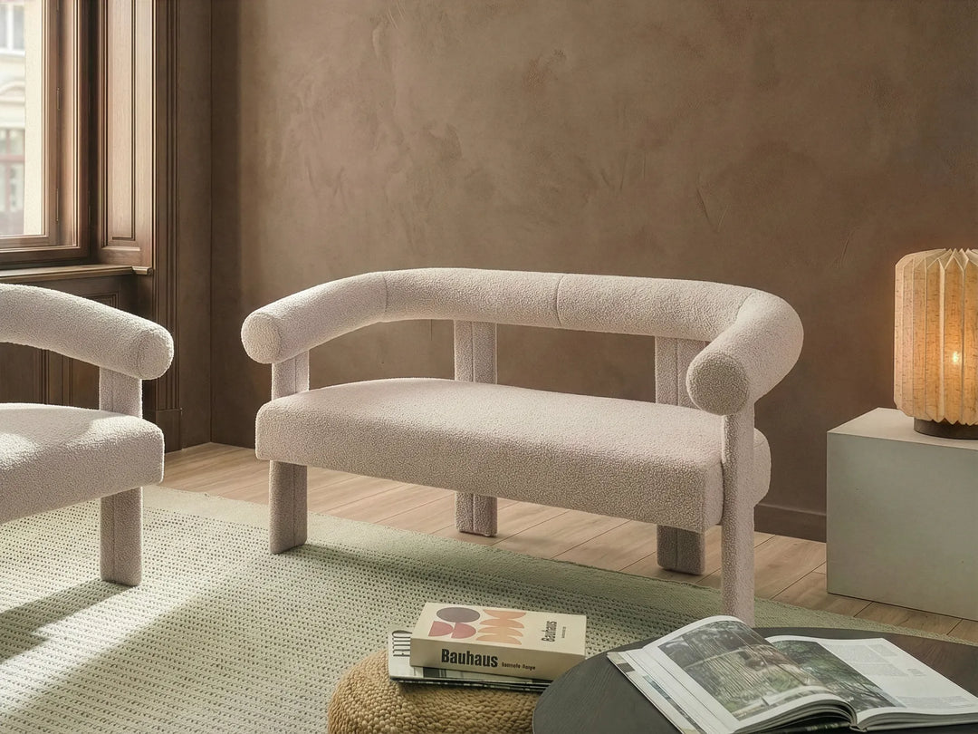 Beige armchair in a room with a lamp and books on a rug