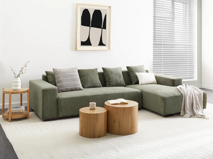 Modern living room with a green sectional sofa, wooden coffee table, and abstract art on the wall.