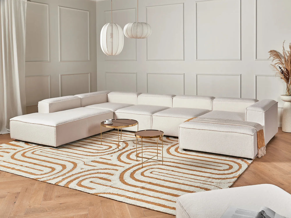 Modern living room with a white sectional sofa, patterned rug, and decorative elements.