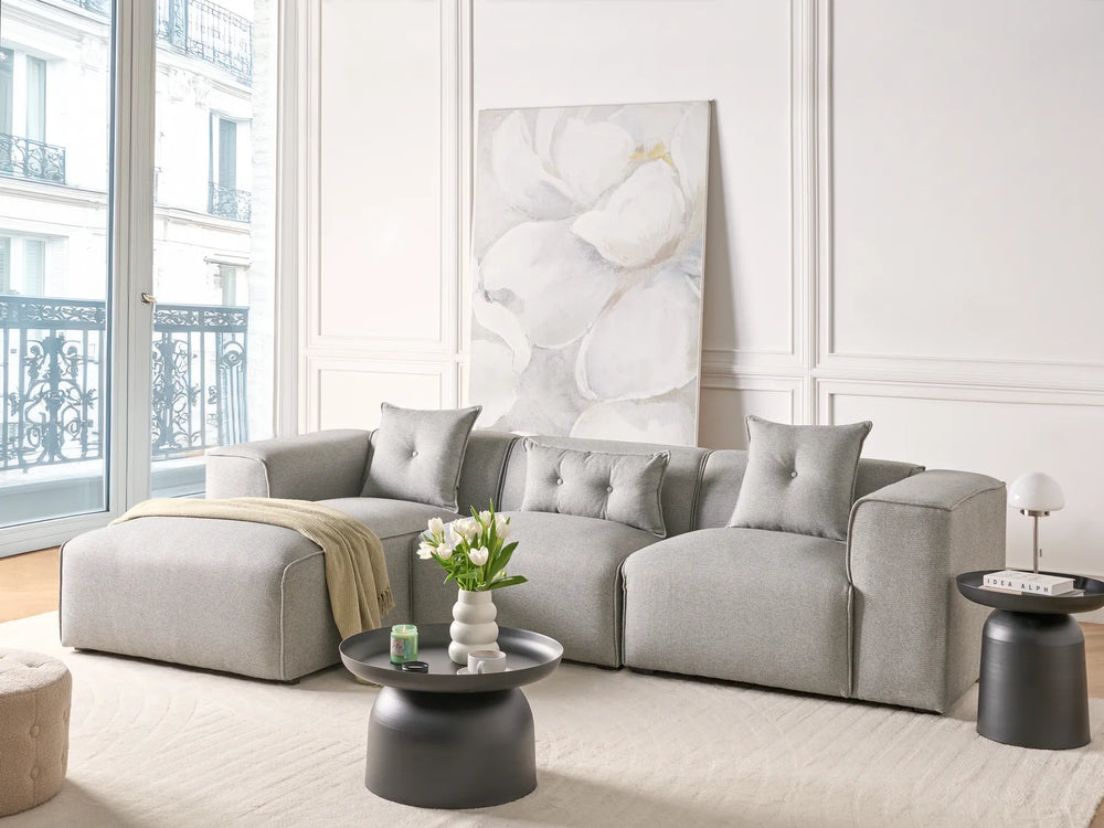 Modern living room with a gray sectional sofa, coffee table, and decorative elements.