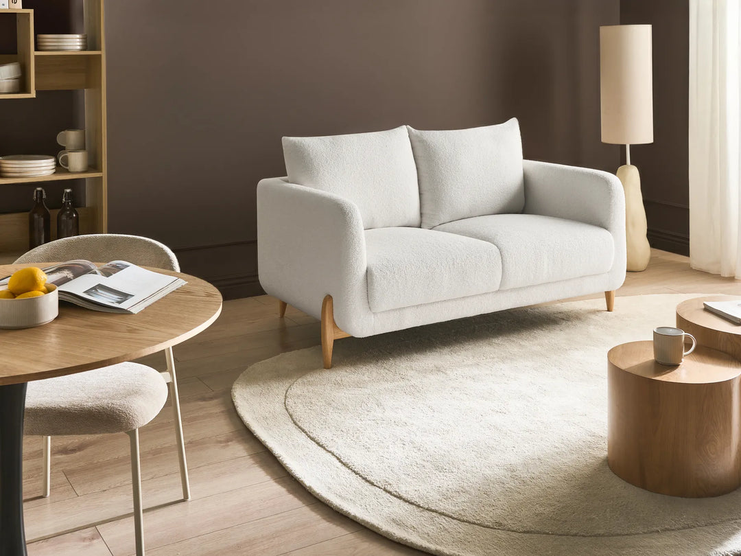 Modern living room with a gray sofa, wooden table, and round rug.